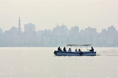 People on boat in river against sky