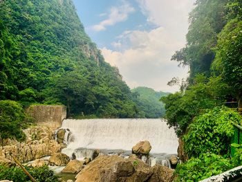 Scenic view of waterfall against sky