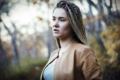 Thoughtful young woman with dreadlocks looking away at public park