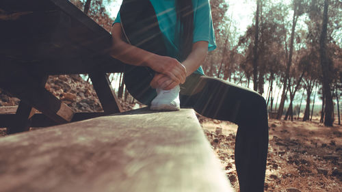 Midsection of woman standing by trees in forest