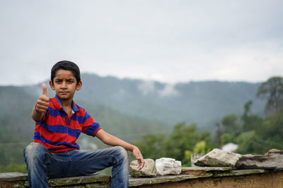 Portrait of a indian pahadi kid who belongs to the mountains showing thumbs up to the camera.