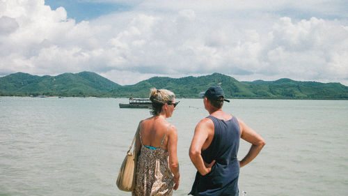 Rear view of men in sea against sky