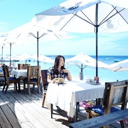 Woman on table by chairs against sky