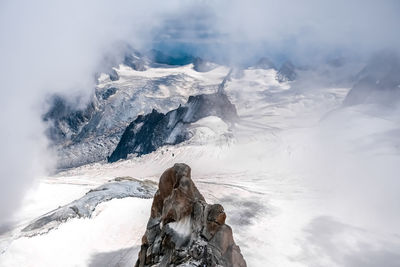 Rear view of woman standing on snow covered mountain against sky