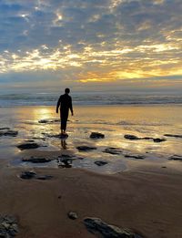 Full length of man on beach against sky during sunset
