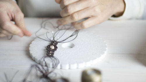 Cropped hands of woman working with thread on table