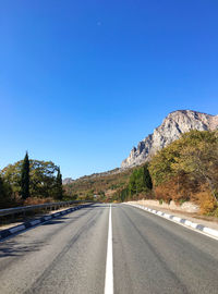 Empty road against clear blue sky