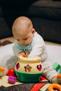 Portrait of cute baby boy playing with sorter toy at home
