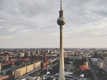 Communications tower in city against sky