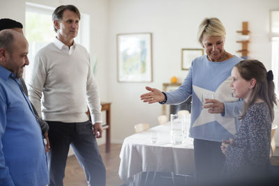 Mother introducing daughter to friends in social gathering at home