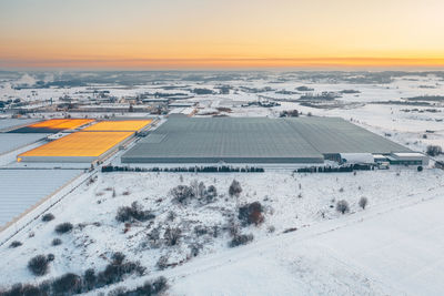 High angle view of snow covered field against sky during sunset