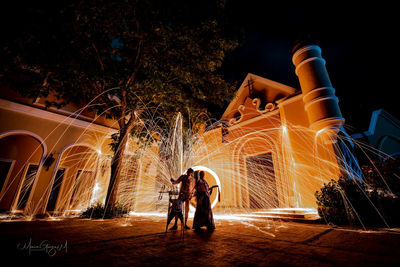 People standing against illuminated building at night