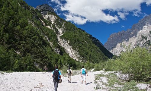 Rear view of men walking on mountain against sky