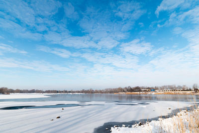 Scenic view of lake against blue sky during winter