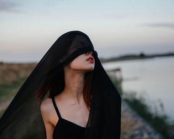 Portrait of woman standing against water