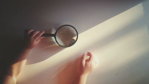 Midsection of person holding glass against white wall