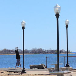 Woman standing by railing against blue sky