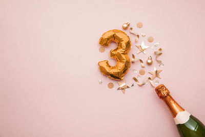 Directly above shot of pills spilling from bottle against pink background