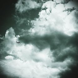 Low angle view of bird flying against cloudy sky