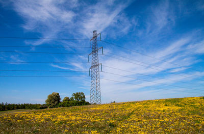 Low angle view of electricity pylon on field against sky