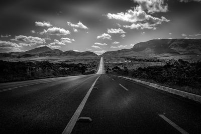 Road leading towards mountains against sky