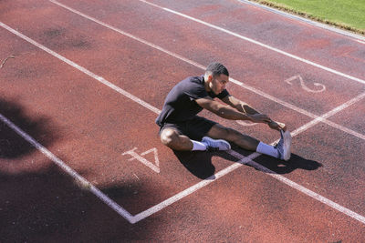 African american athlete stretching on running track