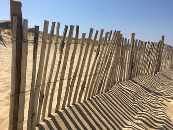 Low angle view of wooden posts against clear sky