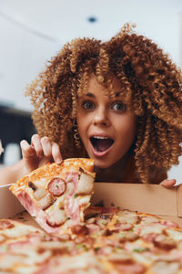 Portrait of young woman holding pizza