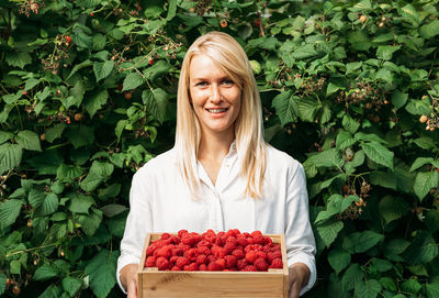 Portrait of smiling young woman holding fruits