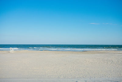 A large empty beach and ocean with a lifeguard chair on a clear blue sky in wildwood new jersey