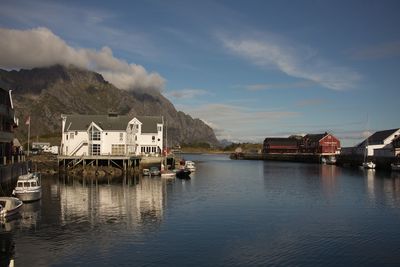 Buildings by river against sky