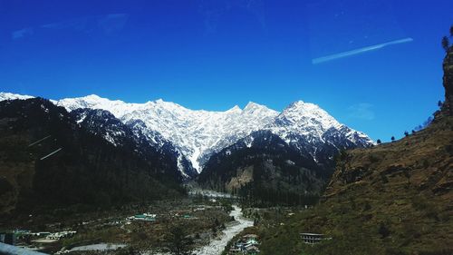 Scenic view of snowcapped mountains against clear blue sky