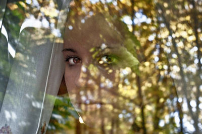 Portrait of young woman looking through tree