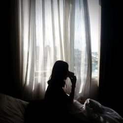 Woman drinking tea while sitting on bed at home