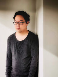 Portrait of young man standing against wall