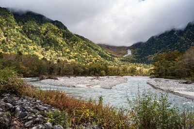 Scenic view of river by mountains against sky