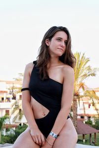 Beautiful young woman standing against clear sky