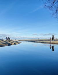 People on water against blue sky