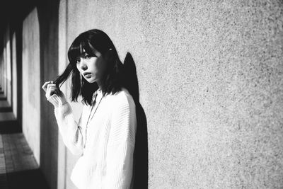 Young woman wearing sunglasses standing against wall