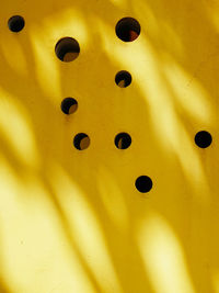 Full frame shot of circular holes on yellow wall