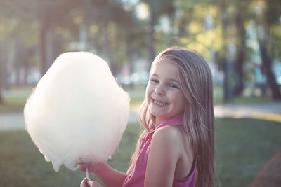 Portrait of smiling girl holding cotton candy outdoors
