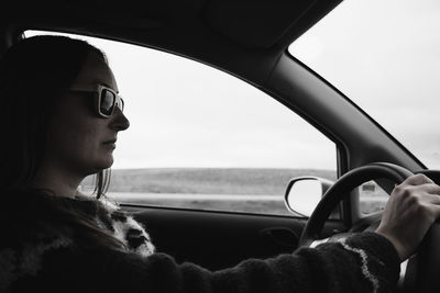 Side view of woman wearing sunglasses while driving car