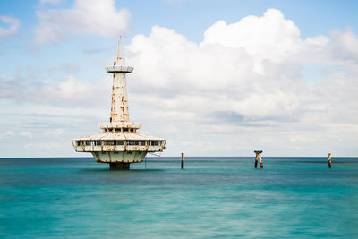 Lighthouse by sea against sky