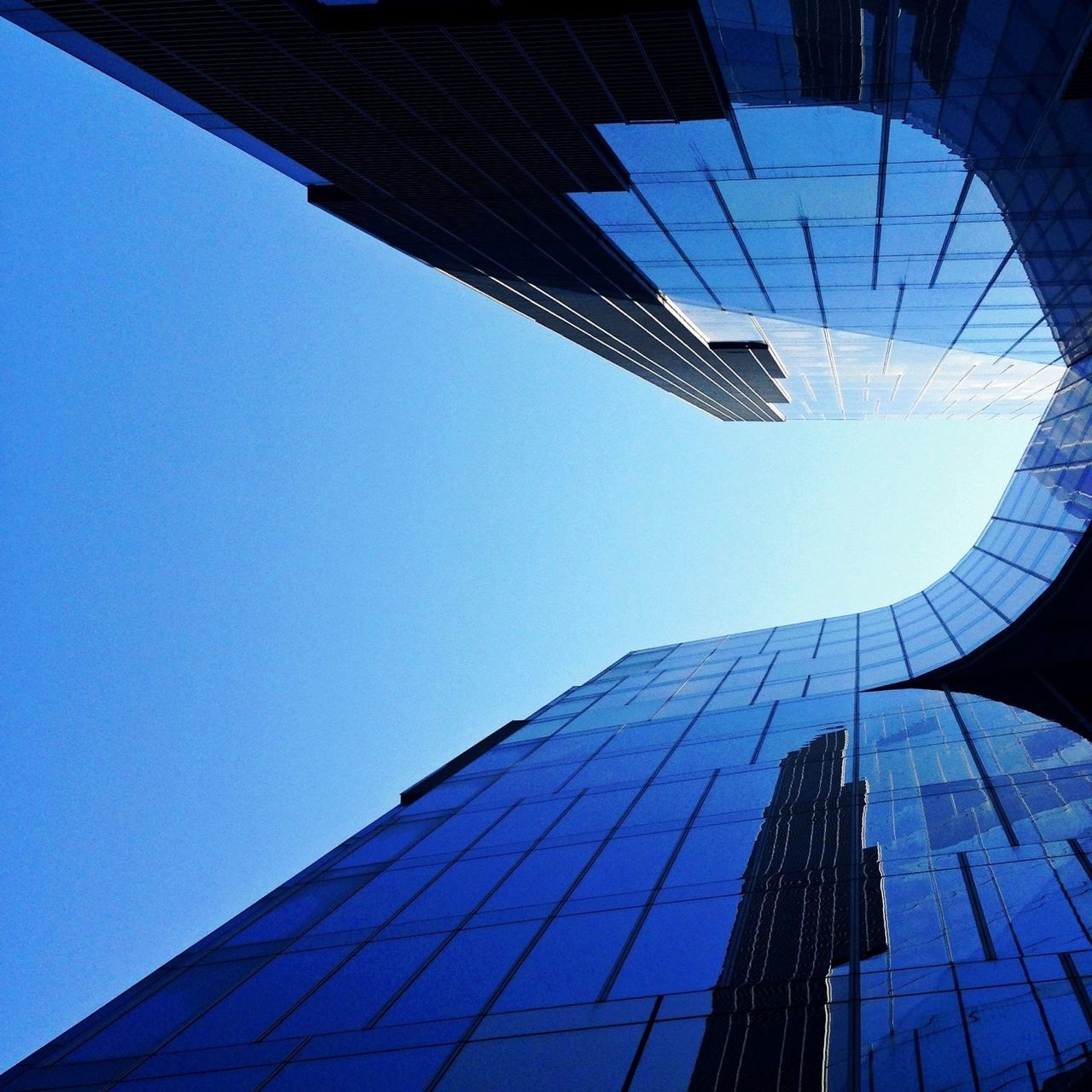 architecture, building exterior, built structure, low angle view, modern, skyscraper, office building, tall - high, city, tower, clear sky, glass - material, reflection, directly below, building, blue, tall, financial district, day, sky