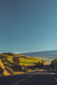 Road passing through landscape against clear sky