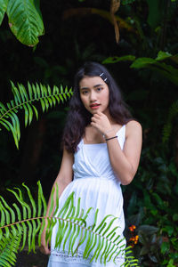 Portrait of young woman standing by plants