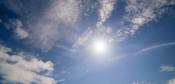 Low angle view of sunlight streaming through clouds