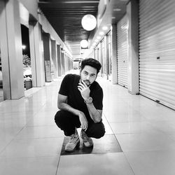 Portrait of young man crouching in corridor