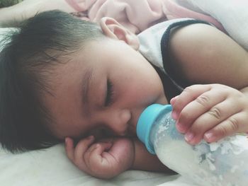 Close-up of baby boy drinking milk on bed at home
