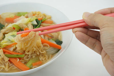 Cropped image of person holding noodles in bowl